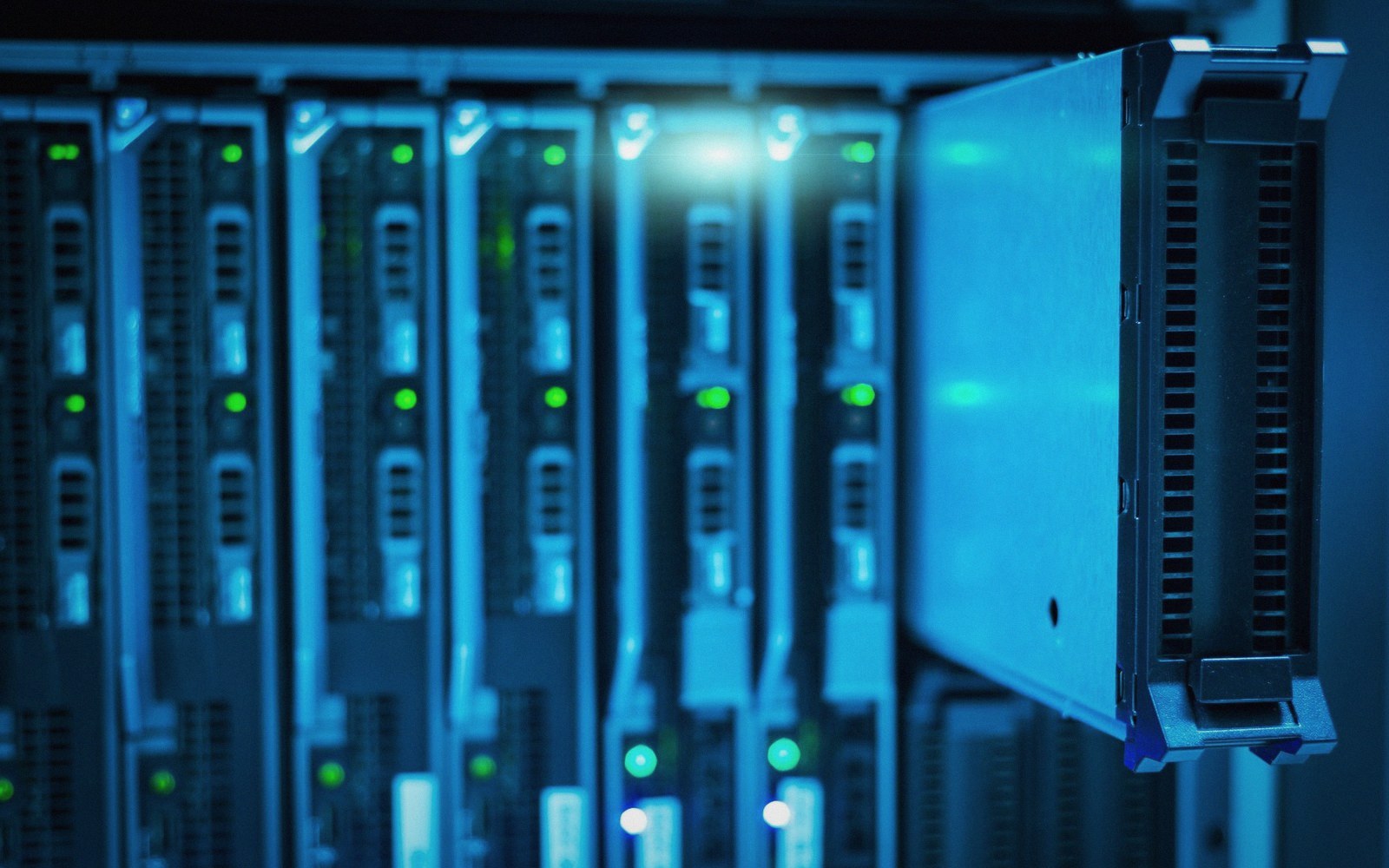 A server blade partially removed from a rack of blinking network equipment